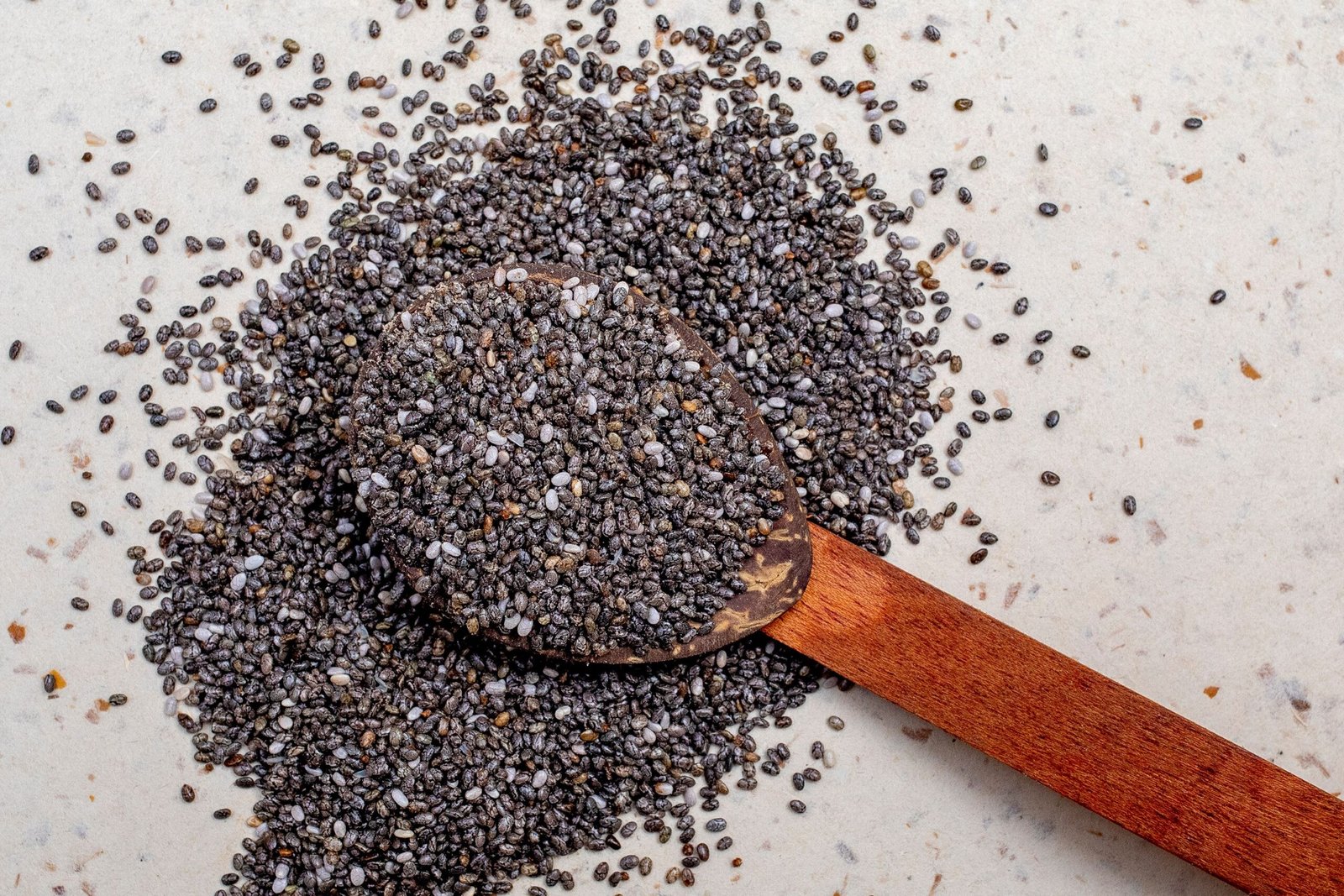 pexels photo 13613853 13613853 Wooden spoon filled with chia seeds, highlighting their texture and nutritional value.