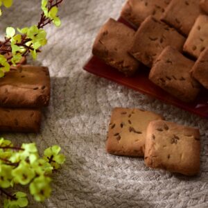 Crisp homemade biscuits arranged on a textured woven mat with vibrant yellow flowers, perfect for a spring snack.