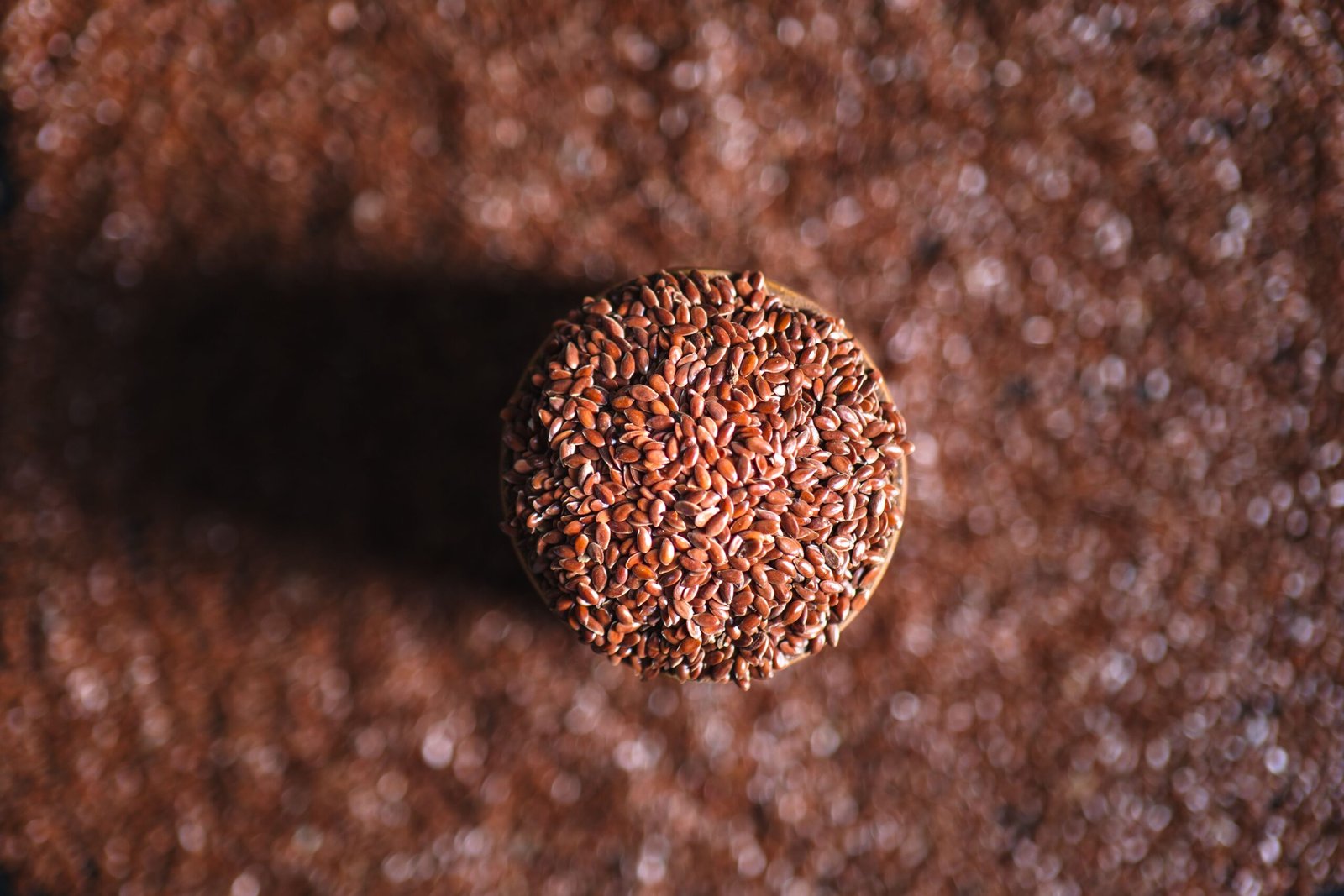 pexels photo 35991162 35991162 A top-down view of a jar filled with flax seeds, surrounded by scattered seeds on the surface.
