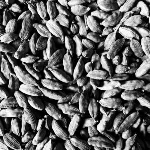 Overhead black and white of textured backdrop representing heap of crunchy cardamon seeds