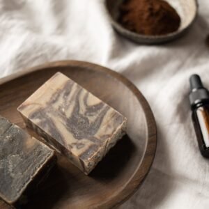 From above of brown handmade soap on timber tray near bowl with fragrant coffee scrub