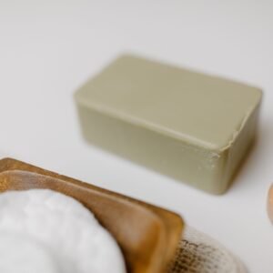 Close-up of a natural soap bar with a wooden brush and cotton pads for skincare.
