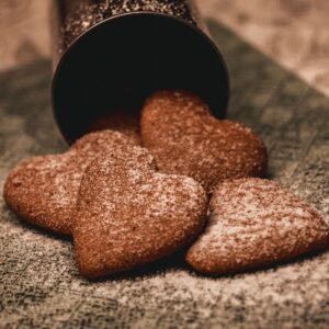 From above of tasty heart shaped chocolate cookies placed on tablecloth and decorated with sugar powder