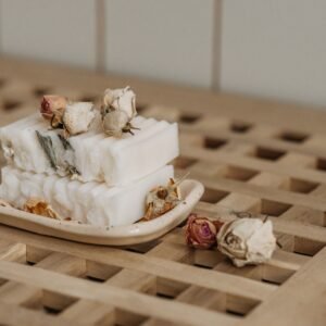 Close-up of natural artisan soaps adorned with dried roses on a ceramic tray, showcasing eco-friendly living.