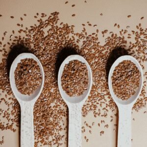 Flat lay of organic flaxseeds in wooden spoons showcasing natural nutrition and texture.