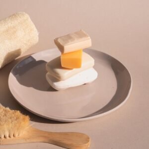 Artistic arrangement of various soaps on a plate with loofah and brush.