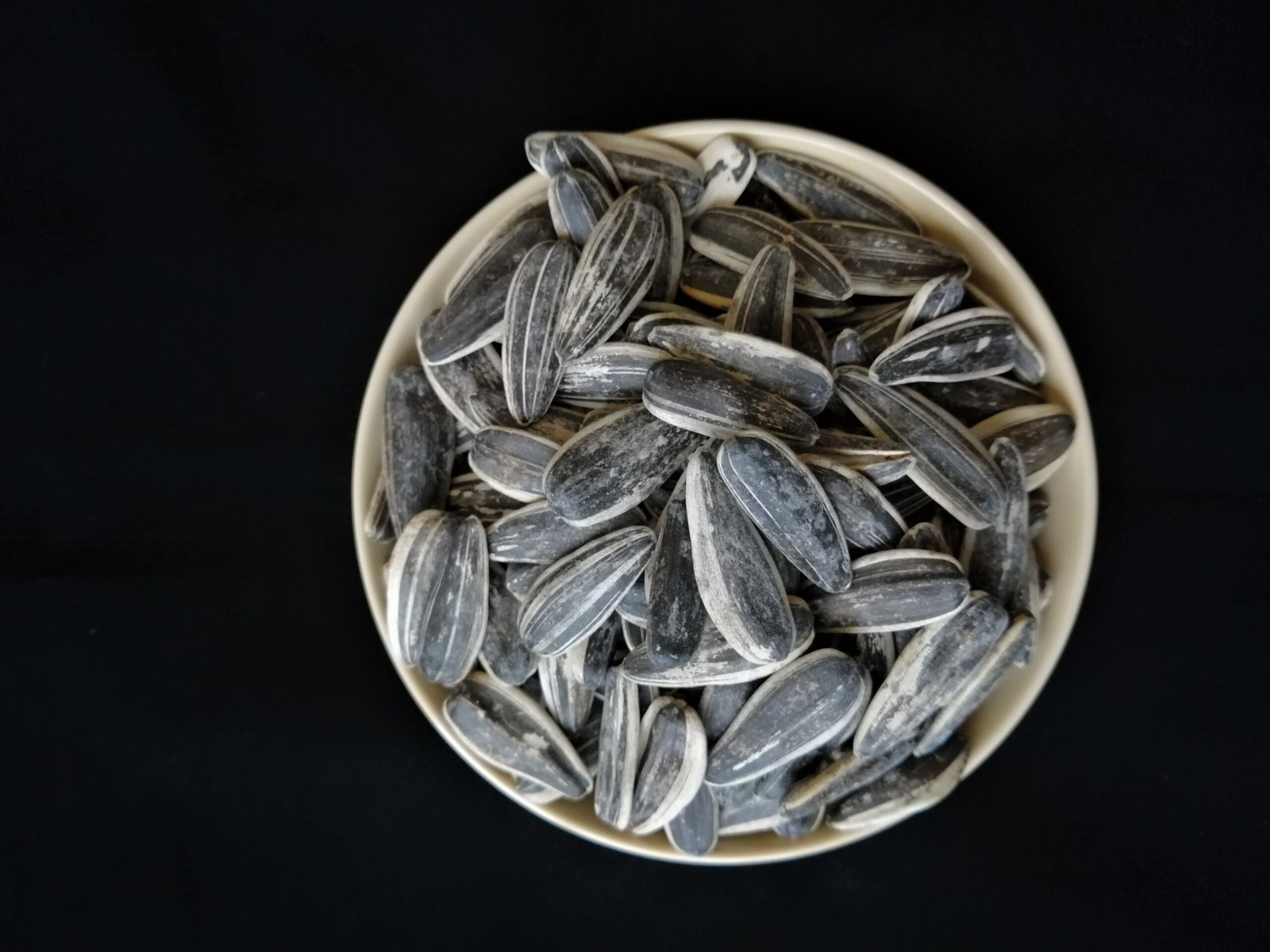 pexels photo 9186961 9186961 Bowl of sunflower seeds on a black background, perfect for healthy food themes.